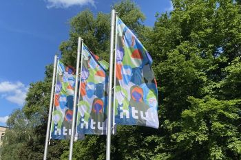 Fahnen am Campus Treskowallee. Das bunte, grafische Motiv zeigt unterschiedliche Menschen.