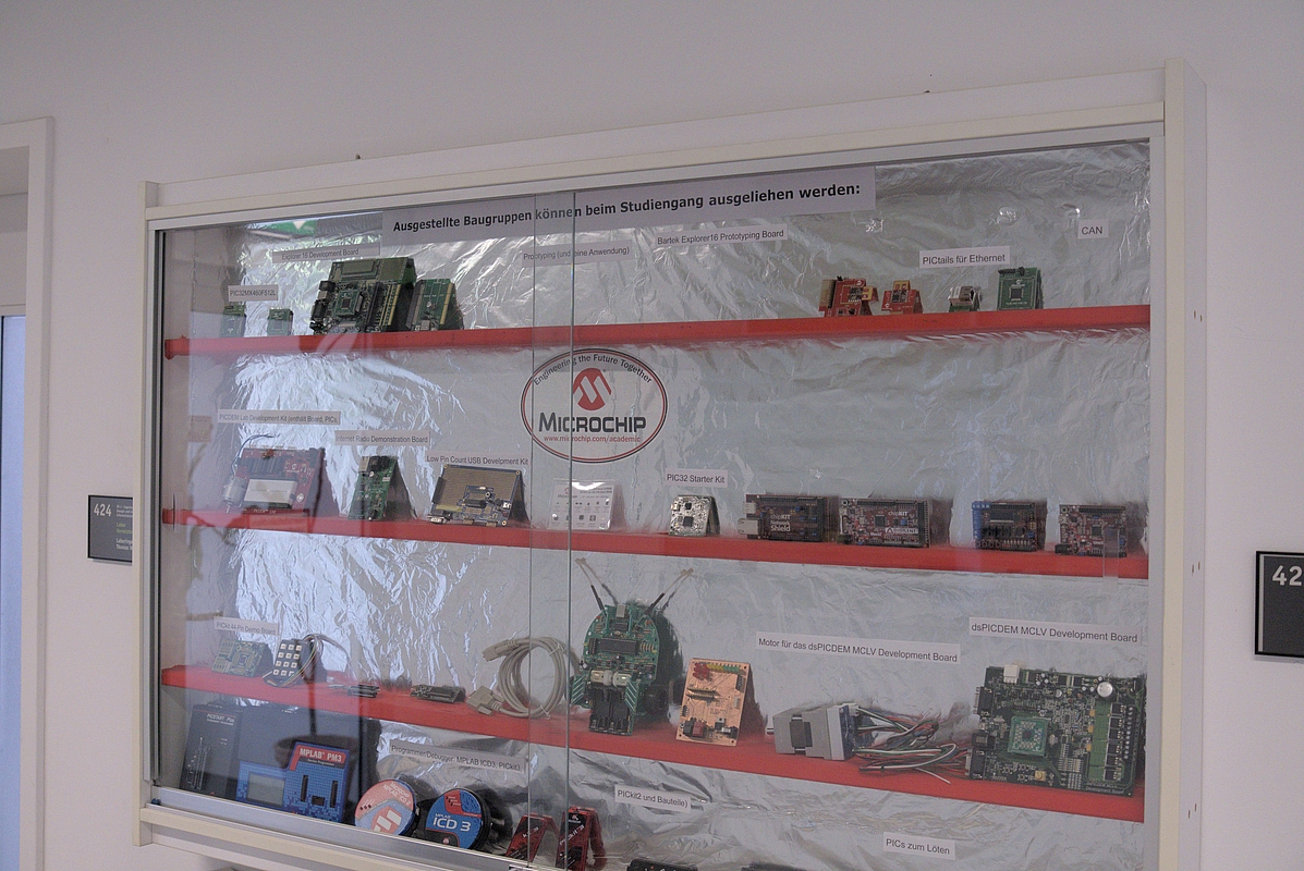 Vitrine mit verschiedenen Mikrocontroller- und Entwicklungsboards von Microchip, die von Studierenden ausgeliehen werden können.